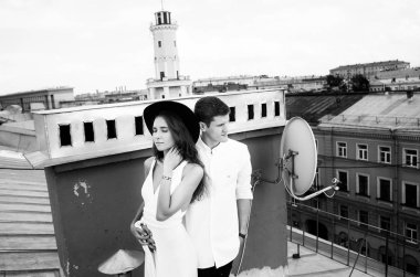 seven çift - beyaz elbise ve şapka ve bir adam bir kız - sarılma ve gülüyor, şehrin çatısı görünümünden, olumlu ve samimi duygular aşk çatıda bir yolda