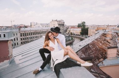 seven çift - beyaz elbise ve şapka bir adamla bir kız - sarılma ve gülüyor, şehrin pozitif ve samimi duygular aşk çatısı görünümünden çatıda bir yolda