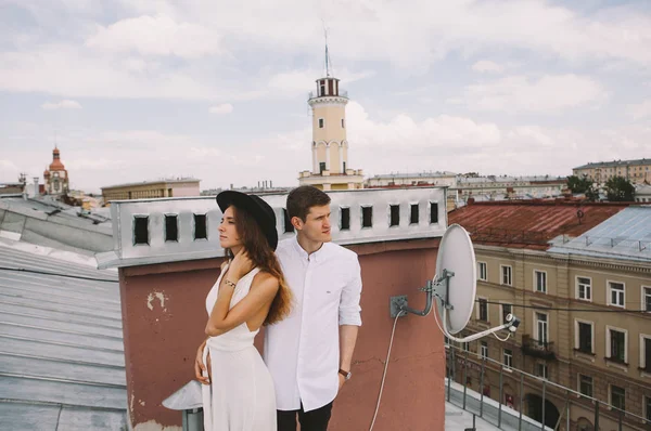 ハグと笑って 都市の屋上からの景色 愛の感情を肯定的な誠実な屋根の上歩くカップル 白いドレスと帽子と男の少女 を愛する — ストック写真