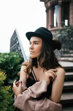 Siyah elbise, pastel pembe ceket ve Ortaçağ Şatosunda poz şapka seksi kız