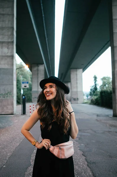 Sexy Brunette Black Dress Hat Pink Purse Poses Stone Bridge — Stock Photo, Image