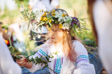 sevimli kız sarışın beyaz Ulusal elbiseli bir çelenk çiçek ve çim bahar festivali pagan örgüleri.