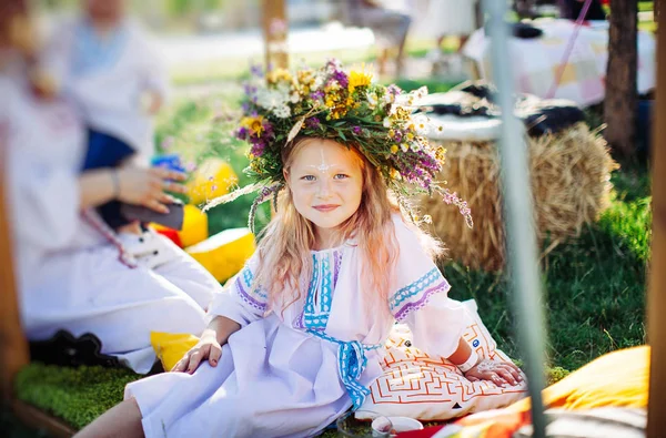 sevimli kız sarışın beyaz Ulusal elbiseli bir çelenk çiçek ve çim bahar festivali pagan örgüleri.