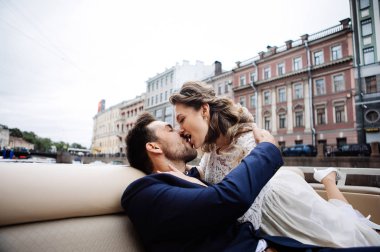 Düğün gününde şık gelin ve damat, nehir üzerinde bir tekne gezisi eğlenmek ve öpüşme 