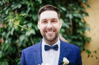 parkta yeşil sarmaşık arka planda gülümseyen mutlu damat