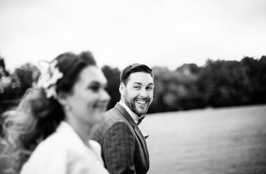 Düğün gününde şık gelin ve damat, eğlenmek ve bir yürüyüş için gülümseyen, siyah beyaz fotoğraf 