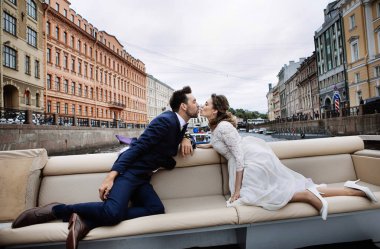 Düğün gününde şık gelin ve damat, nehir üzerinde bir tekne gezisi eğlenmek ve öpüşme 