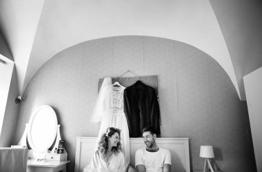 Gelin ve damat sabahı, yatak odasında oturan mutlu severler, siyah beyaz fotoğraf 