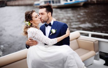 Düğün gününde şık gelin ve damat, nehir üzerinde bir tekne gezisi eğlenmek ve öpüşme 