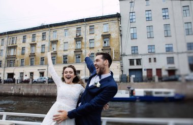 Düğün gününde şık gelin ve damat, nehir üzerinde bir tekne gezisi eğlenmek ve öpüşme 
