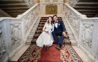 Saray kaydından sonra merdivenlerden oturan mutlu gelin ve damat 