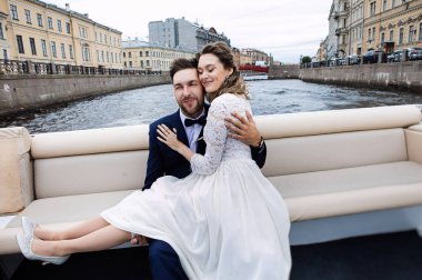 Düğün gününde şık gelin ve damat, nehir üzerinde bir tekne gezisi eğlenmek ve öpüşme 