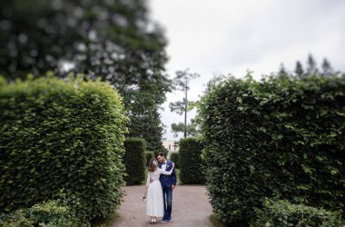 Düğün gününde sarılma ve bir bahar parkında gülümseyen şık gelin ve damat