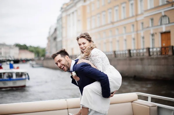 时尚的新娘和新郎在他们的婚礼当天 有乐趣和微笑的船上的河流之旅 — 图库照片