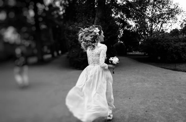金发碧眼的新娘花束运行在公园里 黑色和白色的照片 — 图库照片