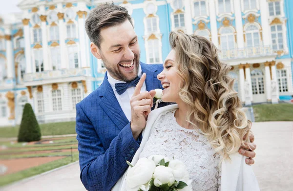 彼らの結婚式の日にスタイリッシュな新郎新婦は 楽しさと宮殿の近くの散歩に微笑んでいる — ストック写真