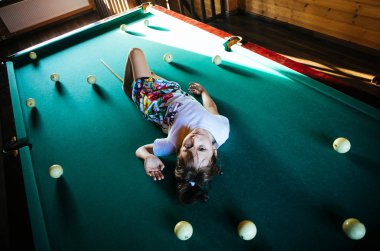 Küçük kız bilardo masasında yatıyor