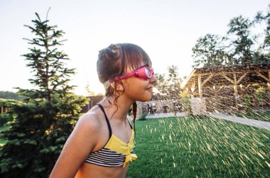 Küçük kız bahçesinde havuz yakınında eğleniyor