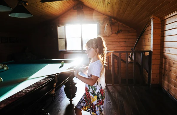 Little girl playing pool at home
