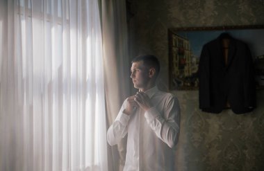 Genç ve şık damat düğün gününde sabahları giyer.