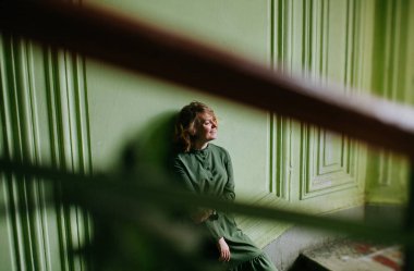 St. Petersburg 'da yeşil bir verandada yeşil elbiseli güzel sarışın kız poz veriyor.