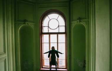 St. Petersburg 'da yeşil bir verandada yeşil elbiseli güzel sarışın kız poz veriyor.