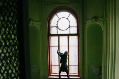 St. Petersburg 'da yeşil bir verandada yeşil elbiseli güzel sarışın kız poz veriyor.