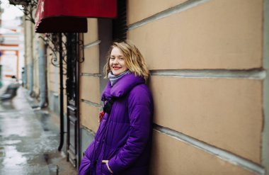 Mor ceketli, kırmızı kemerli sarışın St. Petersburg 'da yürüyor.