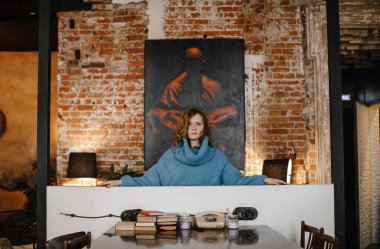 Güzel sarışın kız mavi kazaklı, eski moda iç çamaşırlarıyla poz veriyor.