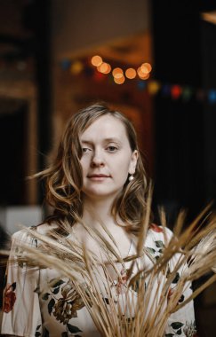 Çiçekli elbiseli güzel sarışın kız eski moda bir iç mekanda poz veriyor.