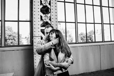 Eski moda ceketli adam gri deri ceketli kız Saint Petersburg 'daki Vitebsk tren istasyonunda yürüyüş yapıyor, mutlu ve sarılıyor.