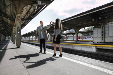 Eski moda ceketli adam gri deri ceketli kız Saint Petersburg 'daki Vitebsk tren istasyonunda yürüyüş yapıyor, mutlu ve sarılıyor.