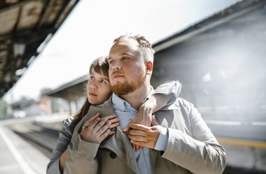 Eski moda ceketli adam gri deri ceketli kız Saint Petersburg 'daki Vitebsk tren istasyonunda yürüyüş yapıyor, mutlu ve sarılıyor.