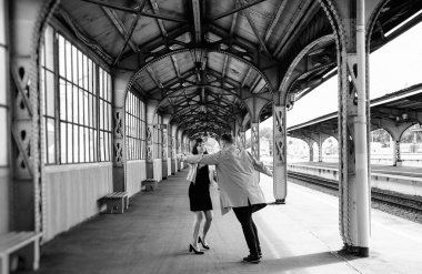 Eski moda ceketli adam gri deri ceketli kız Saint Petersburg 'daki Vitebsk tren istasyonunda yürüyüş yapıyor, mutlu ve sarılıyor.