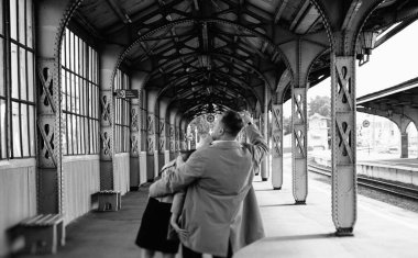 Eski moda ceketli adam gri deri ceketli kız Saint Petersburg 'daki Vitebsk tren istasyonunda yürüyüş yapıyor, mutlu ve sarılıyor.