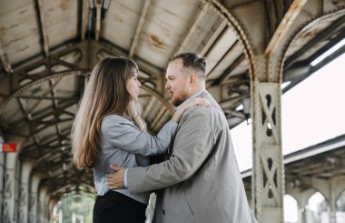 Eski moda ceketli adam gri deri ceketli kız Saint Petersburg 'daki Vitebsk tren istasyonunda yürüyüş yapıyor, mutlu ve sarılıyor.