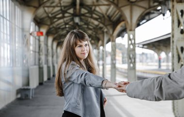 Eski moda ceketli adam gri deri ceketli kız Saint Petersburg 'daki Vitebsk tren istasyonunda yürüyüş yapıyor, mutlu ve sarılıyor.