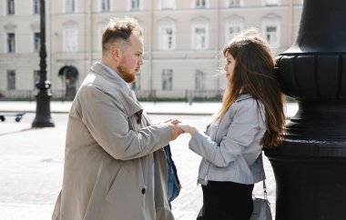 Eski moda ceketli adam gri deri ceketli kız Saint Petersburg 'daki Vitebsk tren istasyonunda yürüyüş yapıyor, mutlu ve sarılıyor.