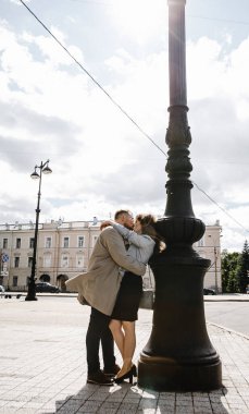 Eski moda ceketli adam gri deri ceketli kız Saint Petersburg 'daki Vitebsk tren istasyonunda yürüyüş yapıyor, mutlu ve sarılıyor.