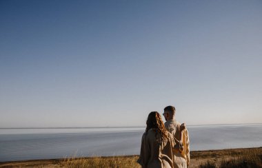 Nişandan sonra gölün yanındaki dağlarda yürüyüş yapan kahverengi tişörtlü şık bir çift. Mutlu erkek ve kız kucaklaşması. Sevgililer Günü için gerçek bir hikaye.