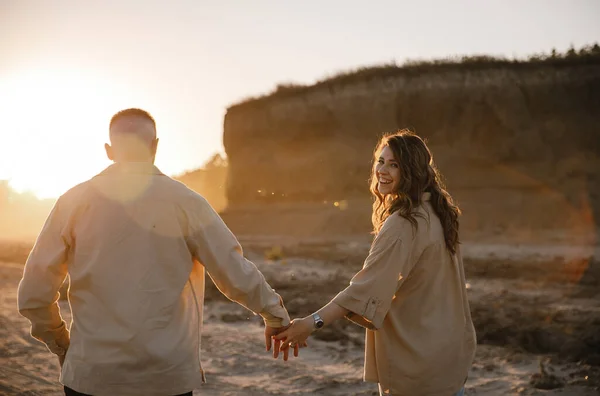 时尚情侣们穿着棕色衬衫在湖边散步 订婚后 快乐的男人和女孩拥抱着 夕阳西下 — 图库照片