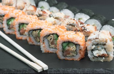 Sushi seti somon balığı peynir salatalık pirinç sosu susam havyar ile çubuklarla alır.