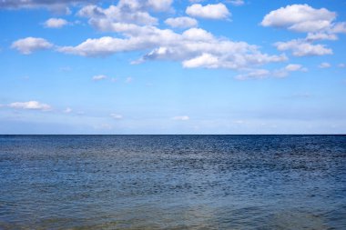 Bulutlu mavi gökyüzüne karşı sakin deniz suları