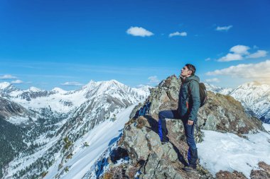 Adam uzun yürüyüşe çıkan kimse üstte duruyor ve gökyüzü ve karlı dağlarda güneşli havalarda bakar. Seyahat ve hedefe ulaşmak