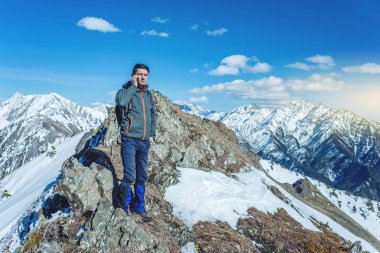 Çin medeniyeti bir zemin üzerine mavi gökyüzü uzak karlı bir dağ tepesinde elinde telefon olan genç bir adam. Etkinlik ve mobil bağlantı kullanılabilirliği kavramı