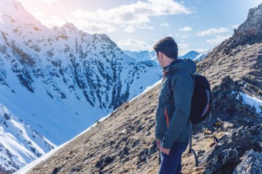 Adam uzun yürüyüşe çıkan kimse üstte duruyor ve gökyüzü ve karlı dağlarda güneşli havalarda bakar. Seyahat ve hedefe ulaşmak