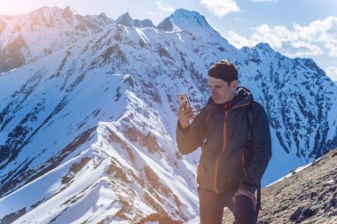 Çin medeniyeti bir zemin üzerine mavi gökyüzü uzak karlı bir dağ tepesinde elinde telefon olan genç bir adam. Etkinlik ve mobil bağlantı kullanılabilirliği kavramı