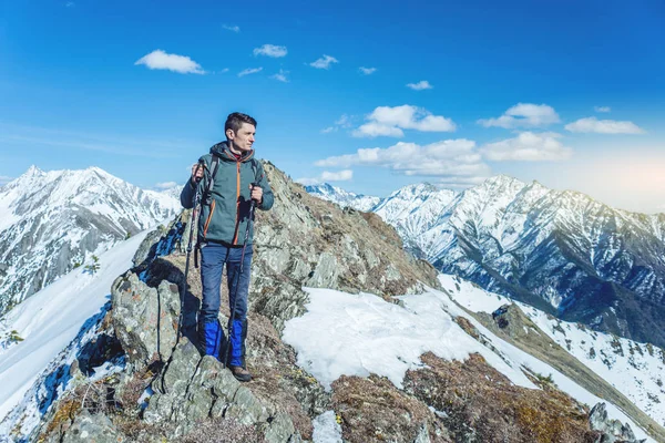 晴れた日の峰の麓で雪の山にトレッキング ポールが男性ハイカーが立っています 概念は旅行し 目標を達成します — ストック写真