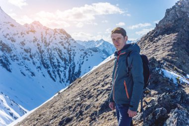 Adam uzun yürüyüşe çıkan kimse üstte duruyor ve gökyüzü ve karlı dağlarda güneşli havalarda bakar. Seyahat ve hedefe ulaşmak