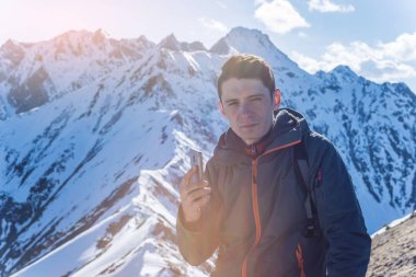 Çin medeniyeti bir zemin üzerine mavi gökyüzü uzak karlı bir dağ tepesinde elinde telefon olan genç bir adam. Etkinlik ve mobil bağlantı kullanılabilirliği kavramı